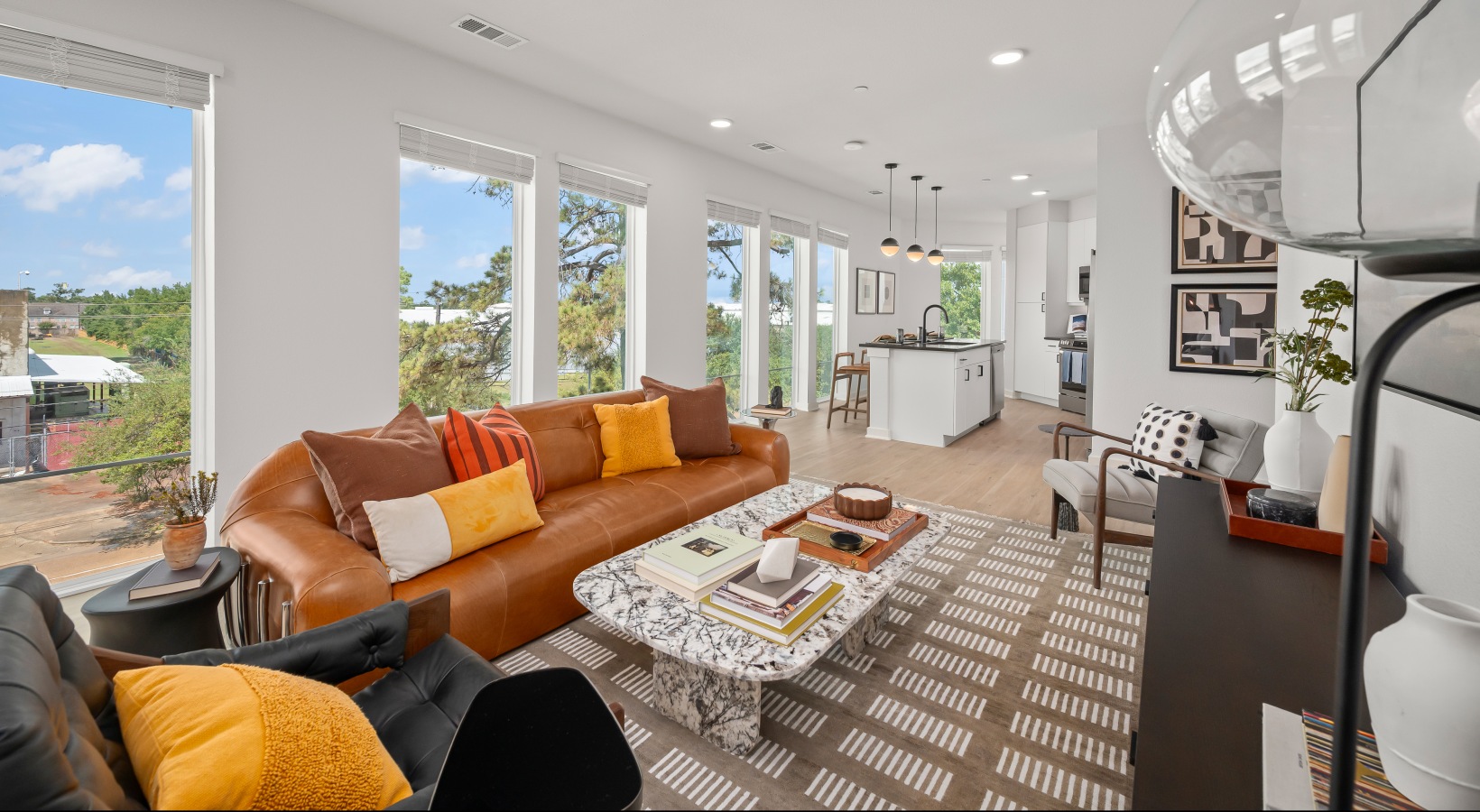 wood flooring and natural lighting living room with floor to ceiling windows behind the couch